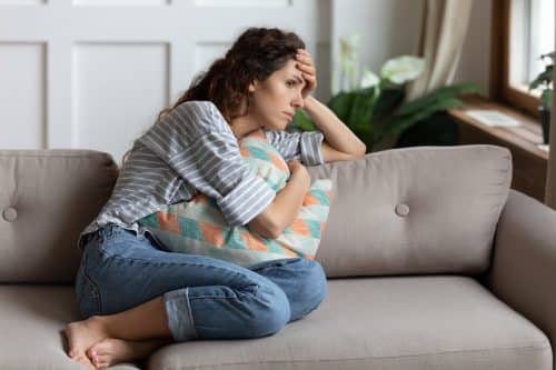 A female sits on her couch fighting her PTSD from a recent car accident.