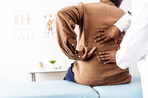 A man shows his doctor where his back hurts after a car accident. 