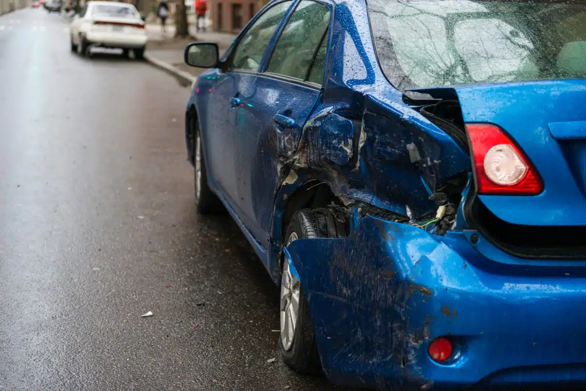 A damaged car parked on the side of the road after a hit-and-run accident.