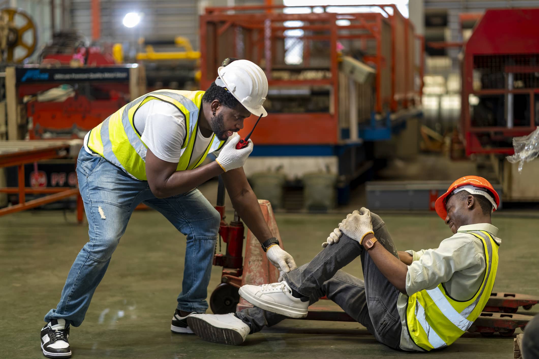 A Baton Rouge factory worker radios for assistance while bending down to help an injured coworker.