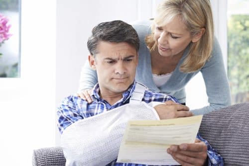 An injured man looking stressed while reading medical bills.