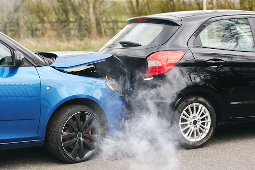 Two cars on the side of the road, damaged after a rear-end collision.