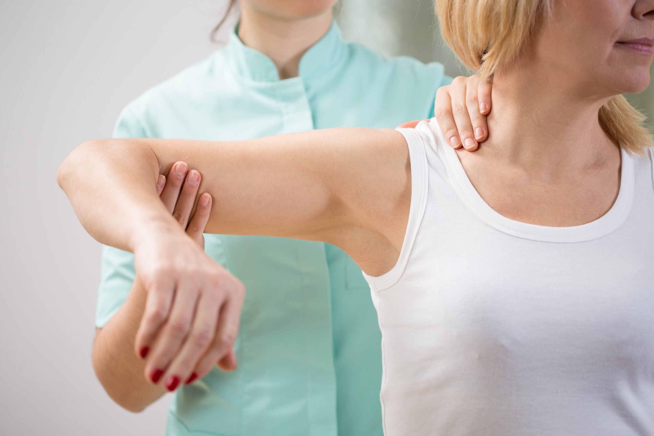 A woman does shoulder exercises at physical therapy